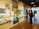The inside of the 4-H History and Learning Center; informational panels and historic photos line the walls while two visitors read the displays.