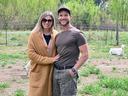 A husband and wife pose at a farm in Durham County with a goat in the background