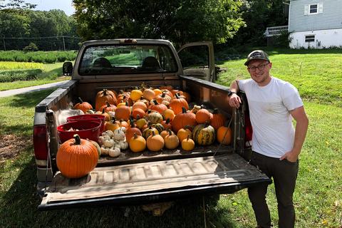 Man with a truck bed full of different kinds of pumpkins
