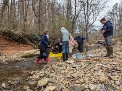People are taking water samples in a stream.