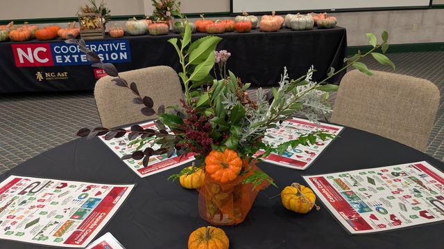 table with fall flowers with NC Cooperative Extension logo behind it