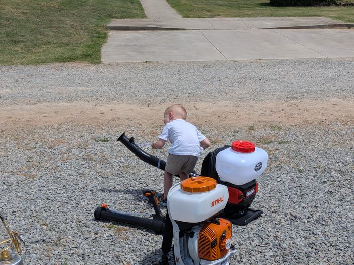 A young boy operates a mosquito blower