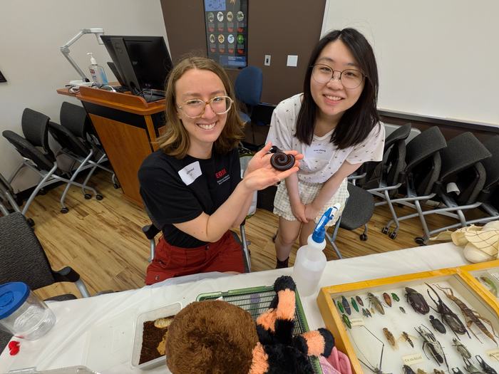 A graduate student holds a giant African millipede while a fellow student stands next to her