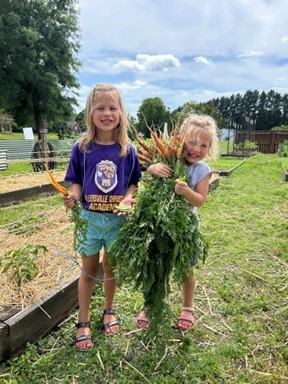 children harvesting vegetables in the community garden