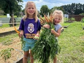 children at the community garden holding carrots they have harvested