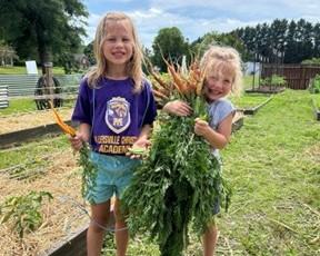 children at the community garden holding carrots they have harvested