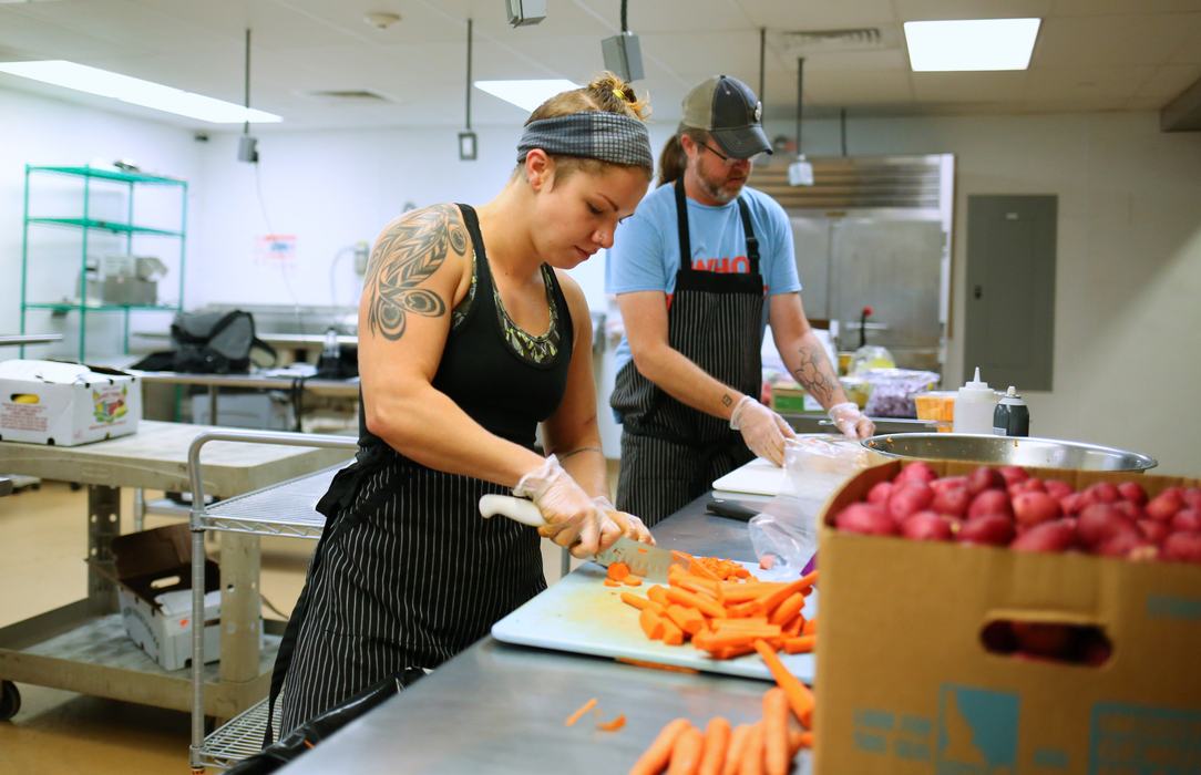 Two people chopping carrots at Piedmont Food Processing Center in the kitchen.