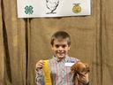 Samson Mills holding his chicken and participation ribbon in front of the Coastal Plains Chicken Show banner
