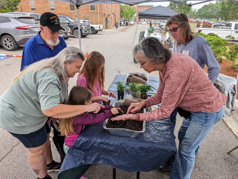 woman helping family with children pot up plants
