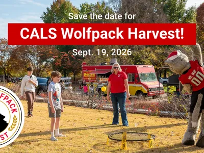 2 youth, one lady, Mr. Wuf from NCSU playing in a yard