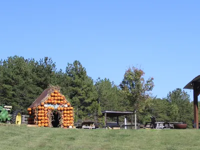 Barn with a tractor and a house made of pumpkins and a silo shelter.