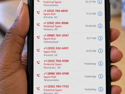 A human hand holds an iPhone displaying a call history filled with suspected spam calls. Several entries show spoofed-looking phone numbers associated with northeastern North Carolina communities, including Ahoskie, Bear Grass, Roper, and Wind