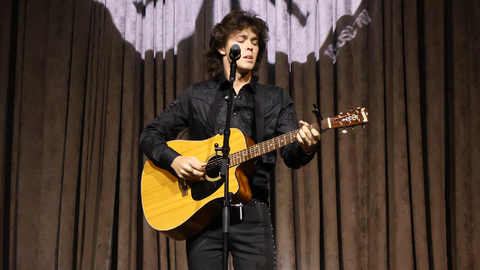 A 4-H member playing an acoustic guitar and singing during the annual Talent Showcase at 4-H Congress.