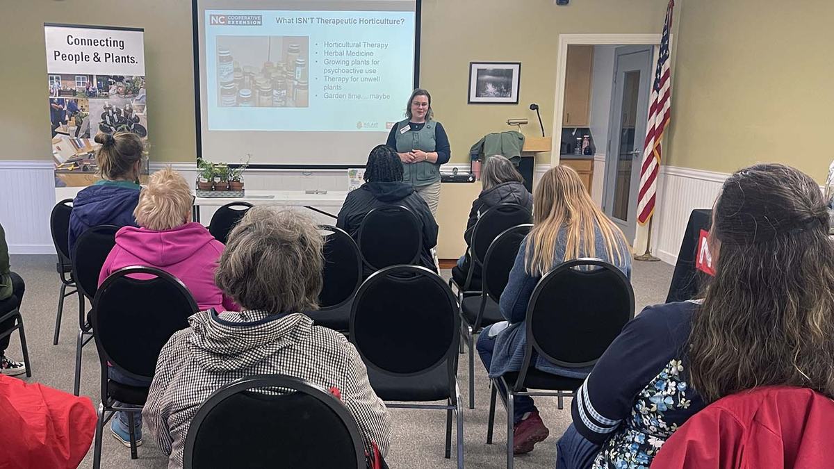 A woman speaks to a class of adults