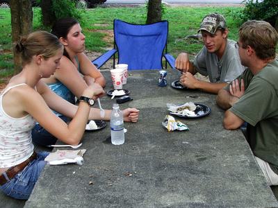 Four people sitting at a picnic table with food