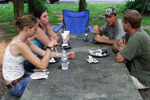 Four people sitting at a picnic table with food