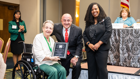 An elderly woman in a wheelchair being recognized with the Dr. Kim Ingold Hands to Larger Service award at the annual NC 4-H Volunteer Leaders' Conference awards banquet.