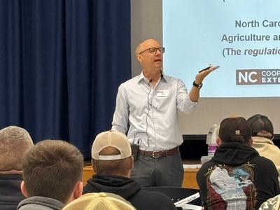Wayne Buhler holding an object in his hand while teaching.