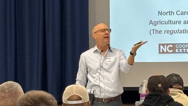Wayne Buhler holding an object in his hand while teaching.