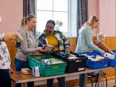 Women and children sort through food donation crates