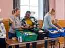 Women and children sort through food donation crates