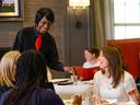 Server standing and interacting at a table with three patrons sitting.