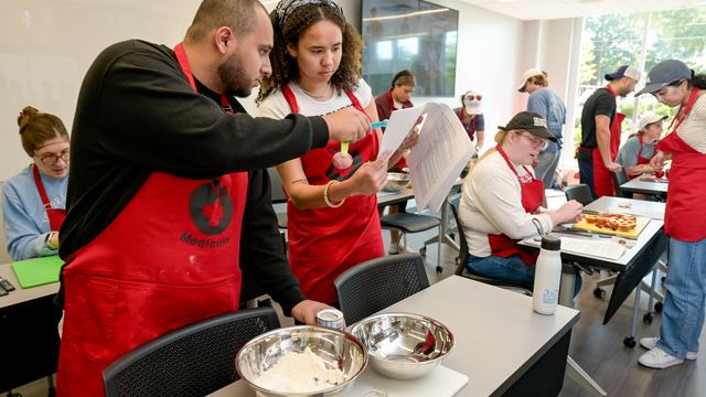 Picture of a man and woman looking at a recipe and cooking.