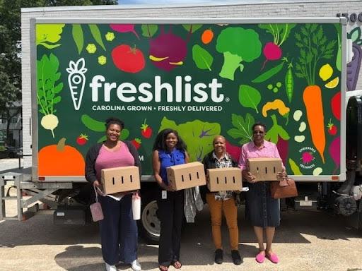 Participants of the event stand in front of the Freshlist truck holding their pre-packaged boxes