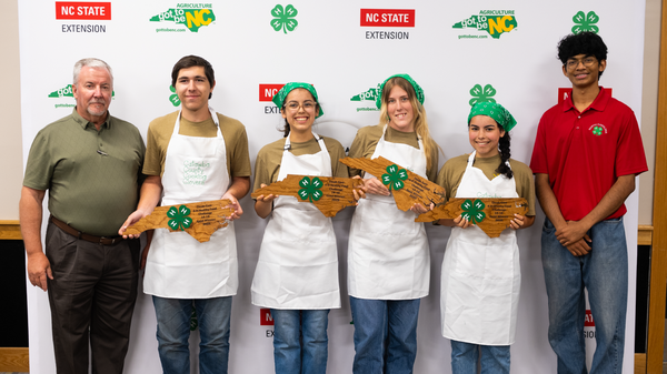 Members of the Catawba County 4-H team stand with the State 4-H Program Leader and State 4-H Council Vice President, holding North Carolina–shaped awards after winning the 2025 Dinah Gore 4-H Healthy Food Challenge.