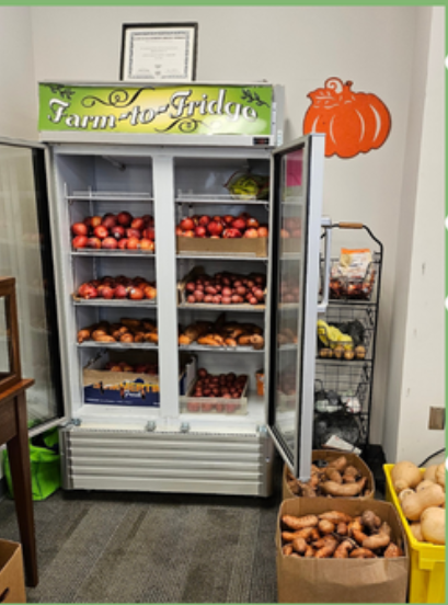 Double door refrigerator filled with produce. Boxes of sweetpotatoes and butternut squash on the ground beside it.