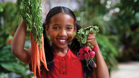 Girl holding up organic produce