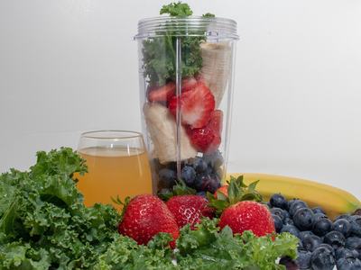 Smoothie fruits and vegetables in and around a blender.  Ingredients for a smoothie.
