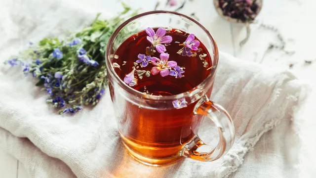 Floral herbs float in a cup of tea.