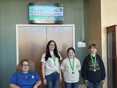 3 kids standing and wearing a medal and an adult in a wheelchair