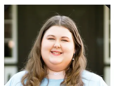 Summer N.C. State intern Katelyn Medlin smiles while standing outside a building.