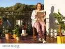 A woman relaxes with her computer tablet on a sunny patio.