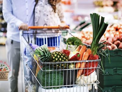 Shopping cart with produce in the produce isle at the grocery store