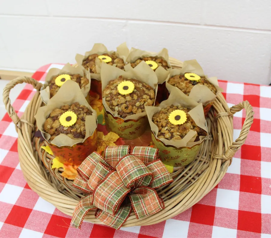 muffins sit in a wicker basket on top of a red gingham tablecloth