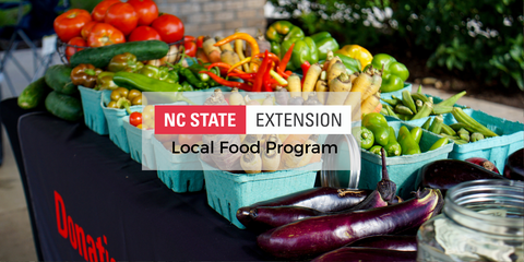 Photo of a NC State Extension Donation Station table with produce and program logo.