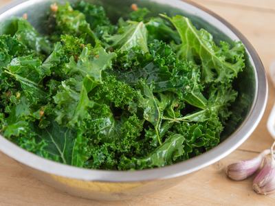 Kale in colander on table with garlic