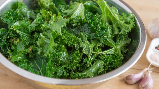 Kale in colander on table with garlic
