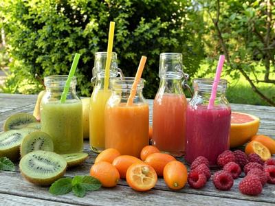 Gemini enhanced image of five colorful fruit smoothies in glass bottles, surrounded by fresh kiwi and berries