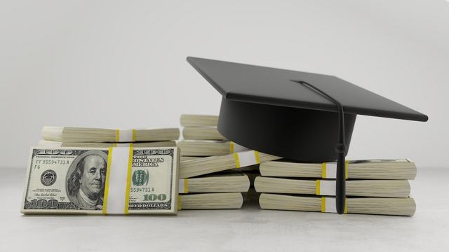 graduation cap on stacks of dollar bills