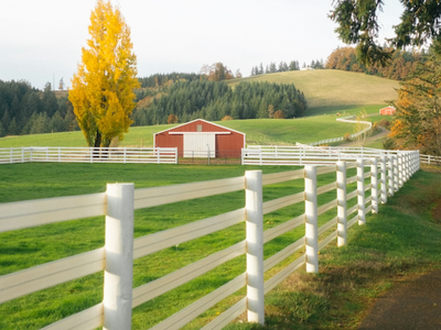 rolling hills with a fenced in pasture and a barn