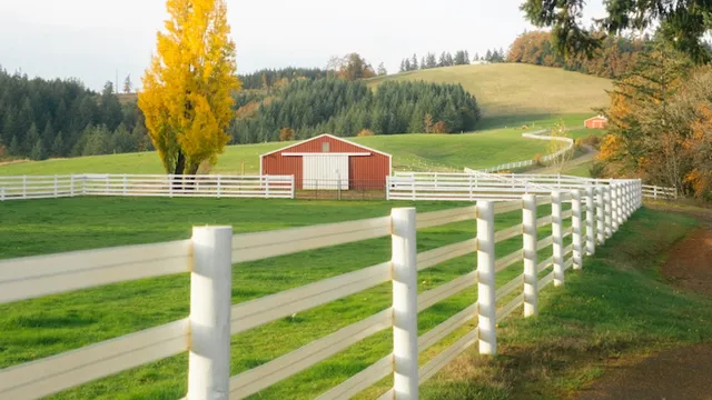 rolling hills with a fenced in pasture and a barn