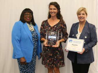 Sarah Ware holding award with two presenters