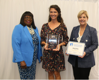 Sarah Ware holding award with two presenters