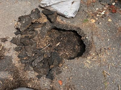 small sinkhole in asphalt driveway