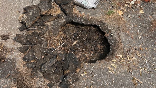 small sinkhole in asphalt driveway