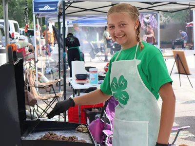 A 4-H member prepares food on a flat-top grill during the Outdoor Cookery competition at the 2026 North Carolina 4-H State Presentation Finals.